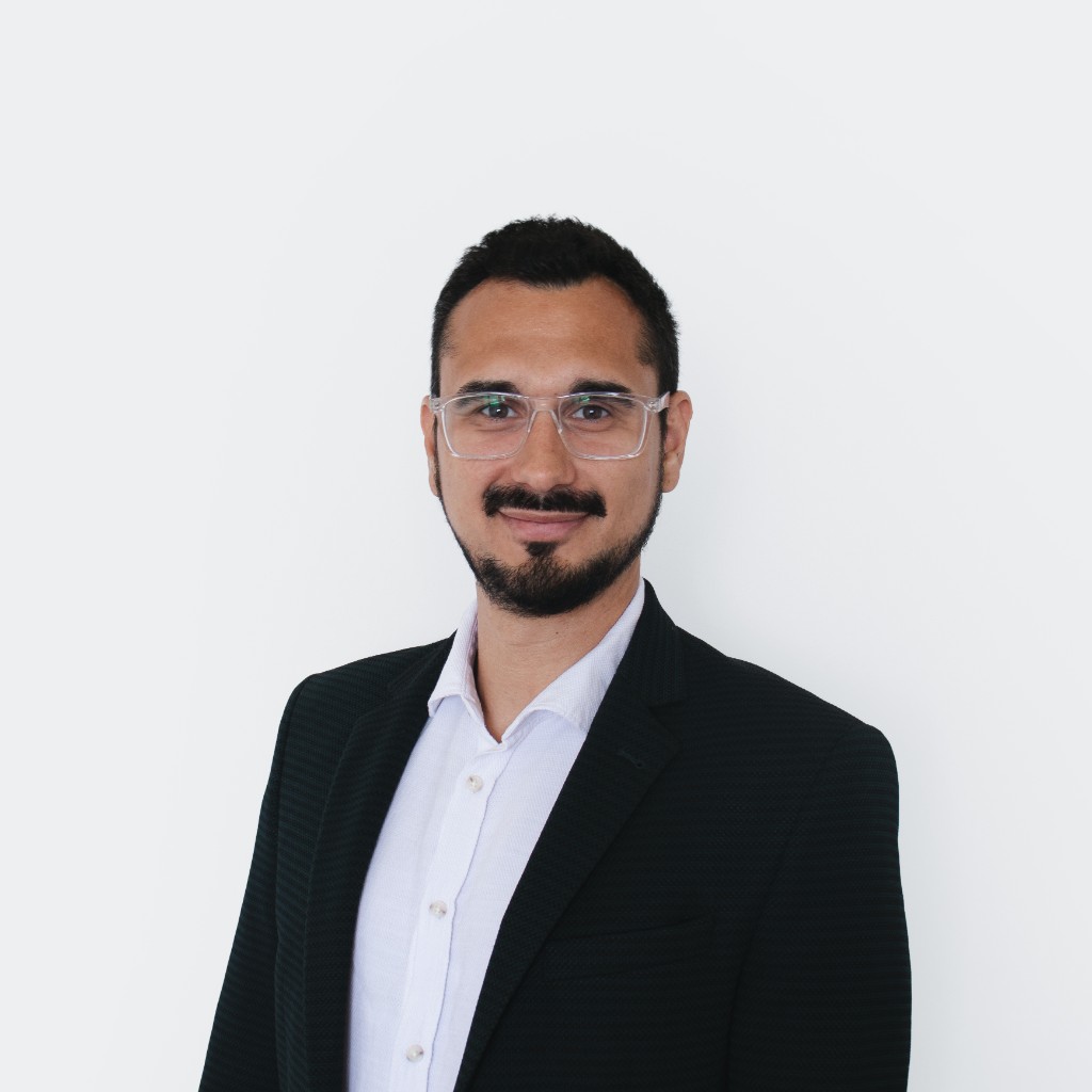 Dr. Miodrag Cekikj - Founder of Adopt Intelligence, wearing glasses and a dark blazer